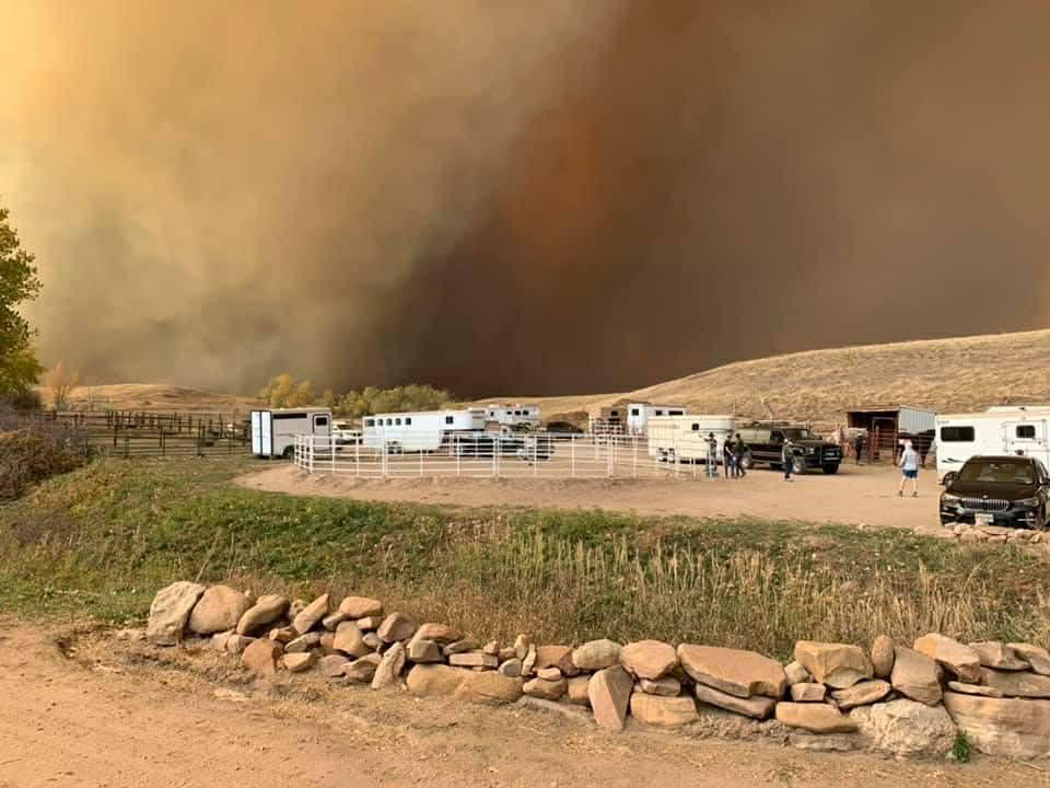 fire evac horse trailers and trucks with smoke and wildfire in background